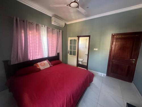 a bedroom with a red bed and a bathroom at RICHGIFT HOMES in New Weija