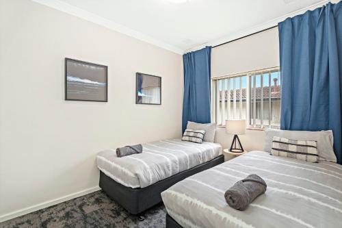 duas camas num quarto com cortinas azuis em 8 Cute Cunningham Close To Subiaco - Sleeps 4 em Perth