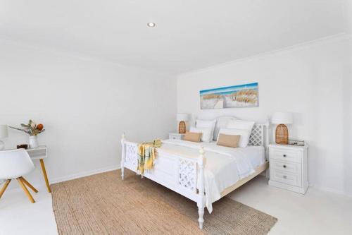 Dormitorio blanco con cama blanca y mesa en ꙮOceanviewꙮGamesroomꙮBBQꙮPetꙮBIG families, en Mandurah