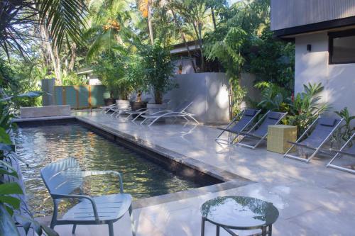 einen Pool mit Stühlen, einem Tisch und Wasser in der Unterkunft D'Palm Villas in Puntarenas