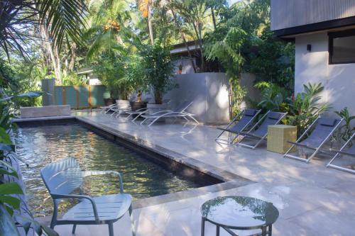 a pool with chairs and a table and water at D'Palm Villas in Puntarenas