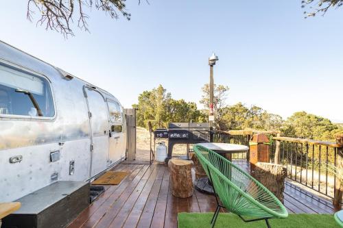 an rv sitting on a deck with a table and a table at Silver Bullet Airstream, El Mistico Glamping Ranch in Nogal