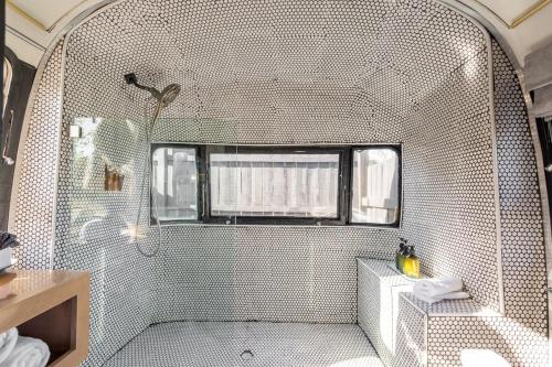 ein Bad mit einer Badewanne und einer Dusche mit einem Fenster in der Unterkunft Silver Bullet Airstream, El Mistico Glamping Ranch in Nogal