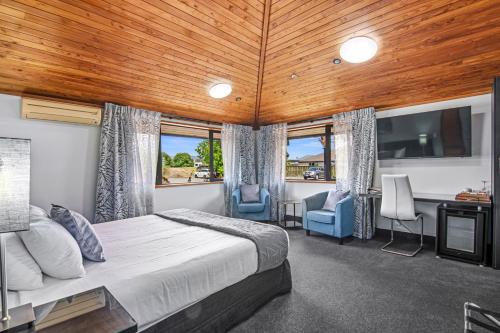 a bedroom with a bed and two chairs and a tv at Riverside Hotel Marlborough in Blenheim