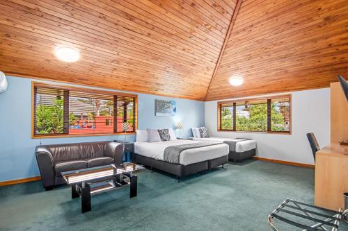 a bedroom with a bed and a couch and windows at Riverside Hotel Marlborough in Blenheim