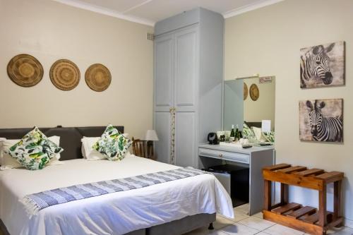 Schlafzimmer mit einem Bett, einem Schreibtisch und einem Spiegel in der Unterkunft African Dreamz Guest House in St Lucia