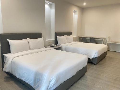 Habitación de hotel con 2 camas con sábanas blancas en GRAND PA Hotel&Resort Lamphun Chiang Mai en Lamphun