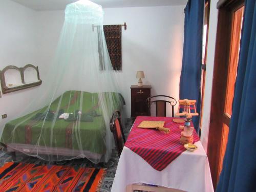 Un dormitorio con una cama verde y una mesa con una mesa. en Posada Del Viajero - Mayan Travelers Inn, en Santa Cruz La Laguna