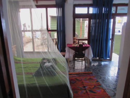 Cette chambre dispose d'une table et d'un lit avec moustiquaire. dans l'établissement Posada Del Viajero - Mayan Travelers Inn, à Santa Cruz La Laguna