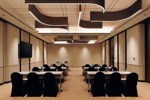 a conference room with tables and chairs and a tv at Hilton Kuching Hotel in Kuching