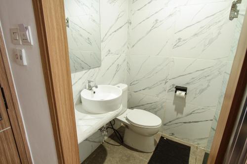 a white bathroom with a toilet and a sink at Sepanak Hotel by Amazing in Curup