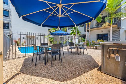 a patio with a table and chairs and a blue umbrella at Hudson Parap in Darwin