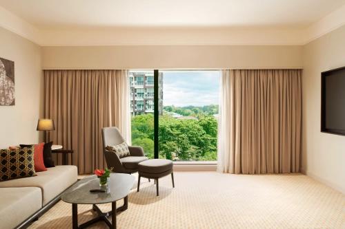 a living room with a couch and chair and a large window at Hilton Kuching Hotel in Kuching