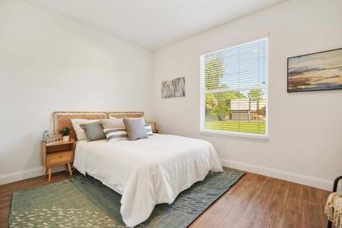 um quarto branco com uma cama e uma janela em Palm Coast Paradise : Cozy 3BR Vacation Retreat em Palm Coast