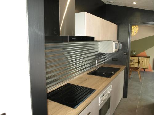 une cuisine avec évier et appareils en acier inoxydable dans l'établissement Charmante maison rénovée en lisière de forêt, 600m de la plage, 2 jardins clos, confort moderne - FR-1-323-371, à Saint-Jean-de-Monts