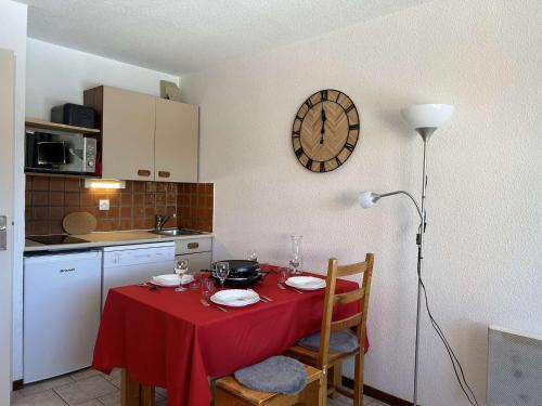 une cuisine avec une table et une horloge au mur dans l'établissement Montgenèvre : Studio rénové, ski aux pieds, 4 pers., parking inclus, animaux acceptés - FR-1-330D-135, à Montgenèvre