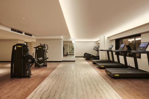 a gym with treadmills and ellipticals in a room at Hilton Kuching Hotel in Kuching