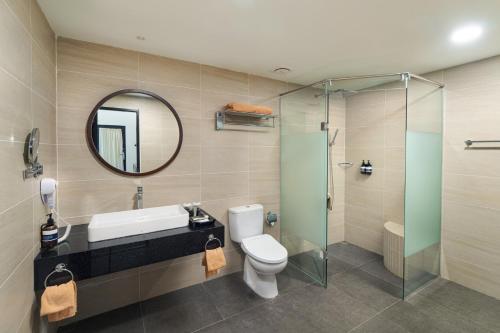 uma casa de banho com um lavatório, um WC e um espelho. em Mayang Sari Beach Resort em Lagoi