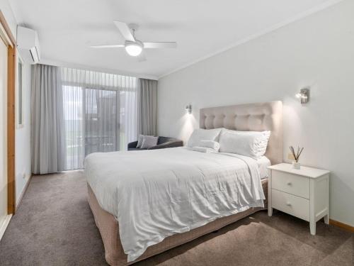 a white bedroom with a large bed and a chair at Yarrawonga Lakeside Apartment 41 in Mulwala