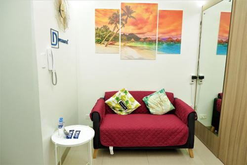 a living room with a red couch and paintings on the wall at Shore Residences MOA Dynastel Staycation in Manila