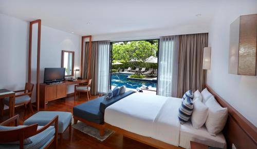 a hotel room with a bed and a view of a pool at Woodlands Suites Serviced Residences - SHA Extra Plus in Pattaya North