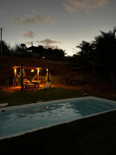 a swimming pool in a backyard with a table and a bench at Casa de praia Aurora in Icapuí