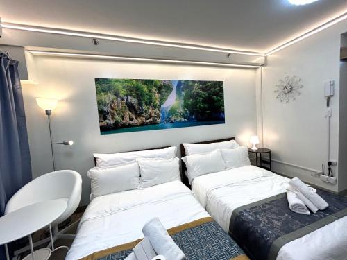 マニラにあるShore Residences MOA Dynastel Staycationの壁に絵画が飾られた部屋のベッド2台