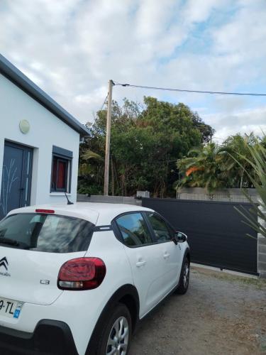 biały samochód zaparkowany przed domem w obiekcie Chez Monblanc w mieście Saint-Joseph