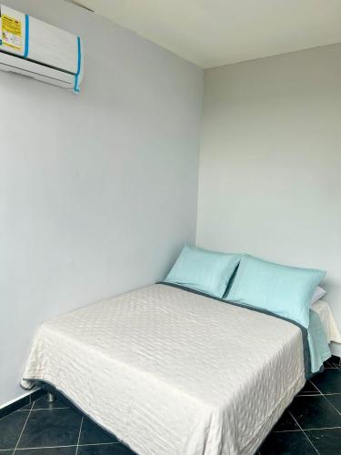 um quarto com uma cama branca e almofadas azuis em Habitación independiente con Terraza en el centro de provenza y P.Lleras em Medellín