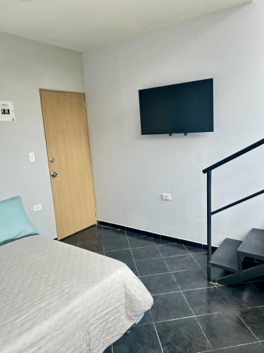 um quarto com uma cama e uma televisão de ecrã plano na parede em Habitación independiente con Terraza en el centro de provenza y P.Lleras em Medellín
