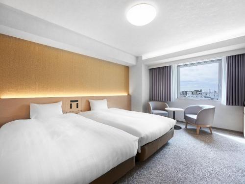 川崎市にあるダイワロイネットホテル川崎の大きなベッドと窓が備わるホテルルームです。