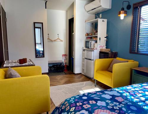 a living room with two yellow chairs and a kitchen at Kiwi House Tokoname VACATION STAY in Tokoname