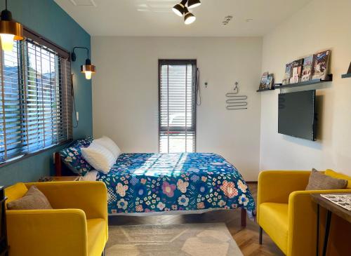 een slaapkamer met een bed en 2 gele stoelen bij Kiwi House Tokoname VACATION STAY in Tokoname