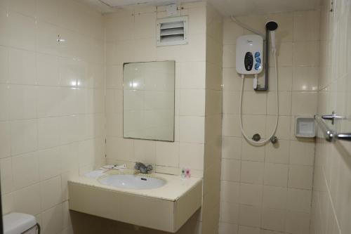 a white bathroom with a sink and a mirror at Hotel Seri Putra in Kuala Lumpur