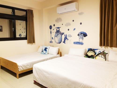 1 Schlafzimmer mit 2 Betten und einer Wand mit Aufklebern in der Unterkunft 馬在對面民宿 in Yilan
