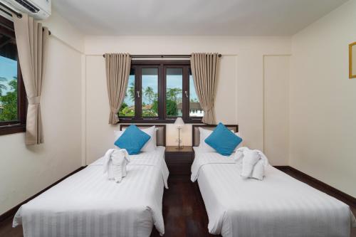 two beds in a room with blue and white pillows at Banyu Biru Villa in Lagoi