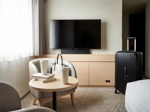 Habitación de hotel con TV y mesa con silla. en Daiwa Roynet Hotel Kawasaki, en Kawasaki