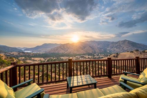 a deck with chairs and a table and the sunset at 4 Kings Log Cabin 150 Acres Spectacular Views in Three Rivers