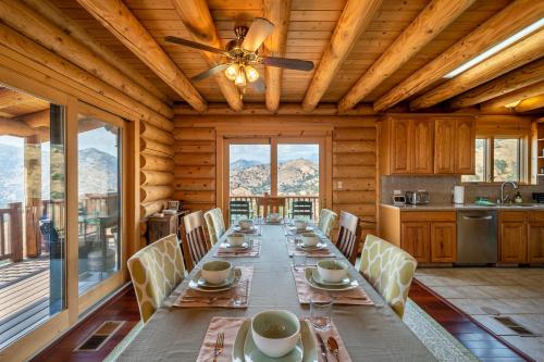 a dining room with a long table and a ceiling fan at 4 Kings Log Cabin 150 Acres Spectacular Views in Three Rivers
