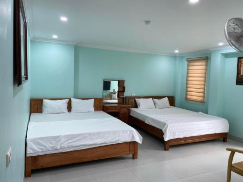 two beds in a room with blue walls at Xuân Hạ Thu Đông Motel in Ha Long