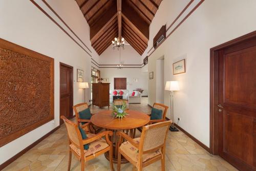 a dining room with a wooden table and chairs at Indra Maya Pool Villas in Lagoi