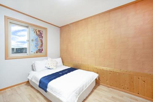 a bedroom with a white bed and a window at Yongmaru Pension in Suncheon