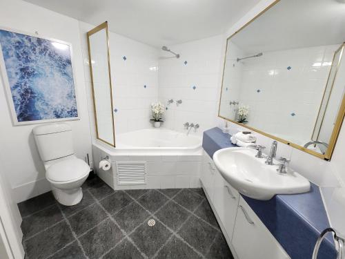 a bathroom with a sink and a toilet and a tub at Fairways Golf & Beach Retreat Bribie Island in Woorim