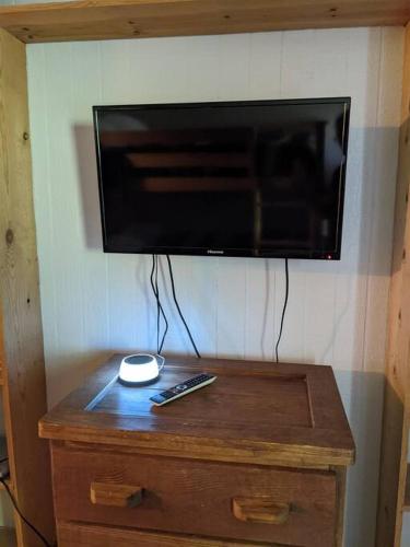 a television on a wall with a wooden table with a remote control at Evergreen Escape At Snowshoe in Snowshoe