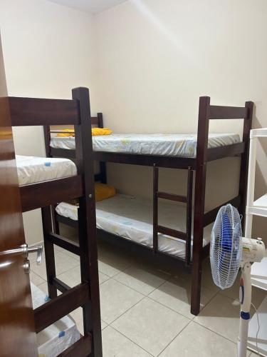 two bunk beds in a room with a fan at Casa em Peruíbe in Peruíbe