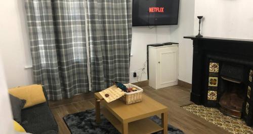 a living room with a table and a fireplace at Contractors Grove 2 Bed House Town Centre Location in Wellingborough