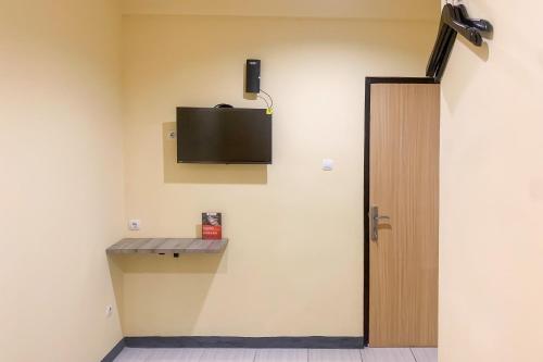 Zimmer mit einem TV an der Wand und einer Tür in der Unterkunft RedDoorz @ Balaraja Centre Plaza in Tangerang