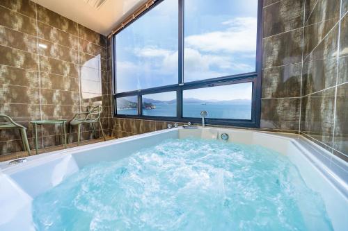 a bathroom with a large tub with a large window at Le Paradis Ocen view Spa Pension in Yeosu
