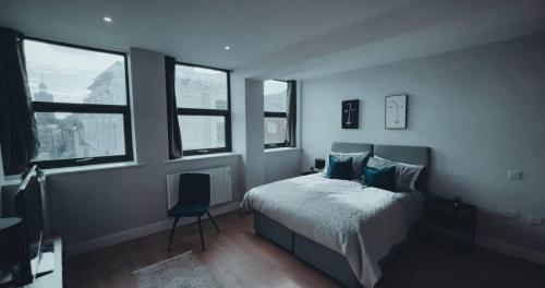 a bedroom with a bed with a chair and windows at Market Haven Kingsize Studios Town Centre with Netflix, Business & Leisure travellers, multiple units available in Northampton