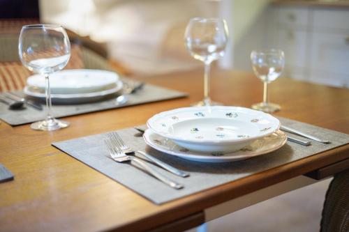 a wooden table with plates and wine glasses on it at Haus Süderende in Keitum